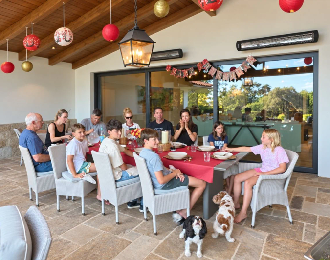 Private hibachi chef cooking on a patio while guests watch from a red-tablecloth dinner table
