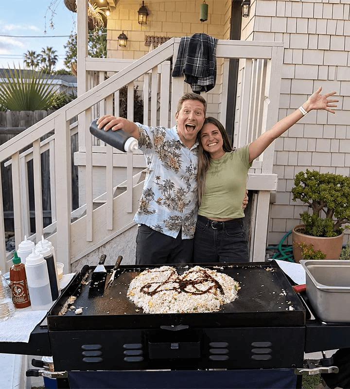 Guests celebrating as the chef finishes heart-shaped fried rice on the grill