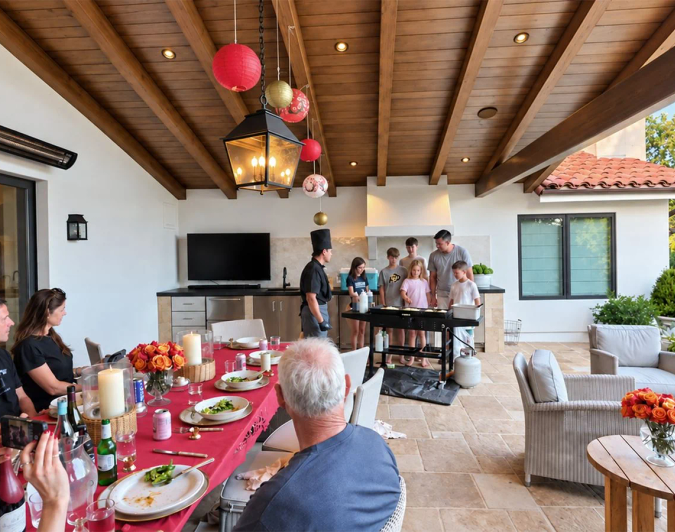 Multi-generational family gathered around a birthday dinner table on a covered patio