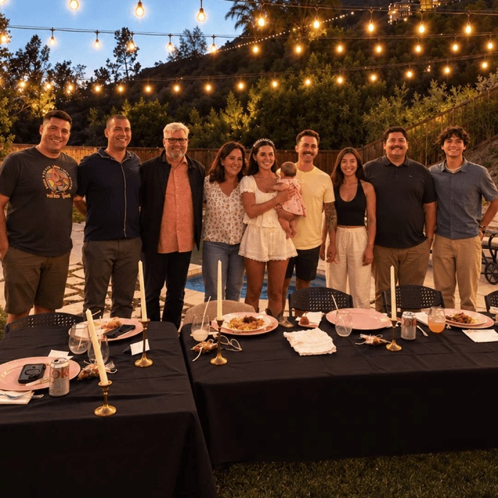 Friends and family posing together at an outdoor hibachi dinner under string lights